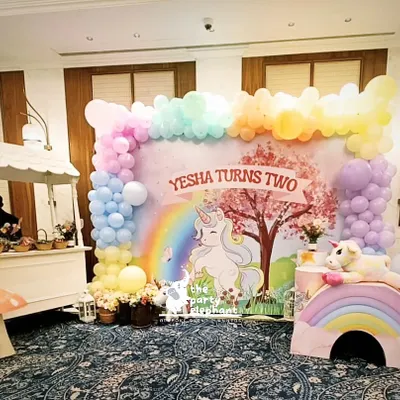 For Yesha's second birthday, I created a whimsical unicorn wonderland. This main backdrop features a custom illustration with a rainbow and unicorn, framed by a pastel balloon garland and complemented by a charming candy cart for treats.