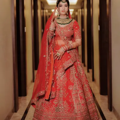 A breathtaking full length portrait of the bride in her magnificent red lehenga. This is a classic, regal shot that showcases the grandeur of a North Indian wedding.