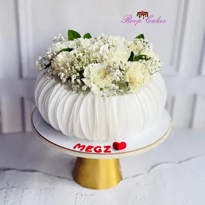 When a cake blooms like a flower vase. This unique design features delicate, pleated wafer paper details and is topped with fresh baby's breath and carnations for a stunning, modern look.