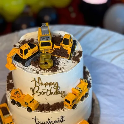 This two-tier construction theme cake is ready for some serious fun! It's decorated with toy excavators and dump trucks digging into a 'dirt' path made of crushed chocolate cookies.