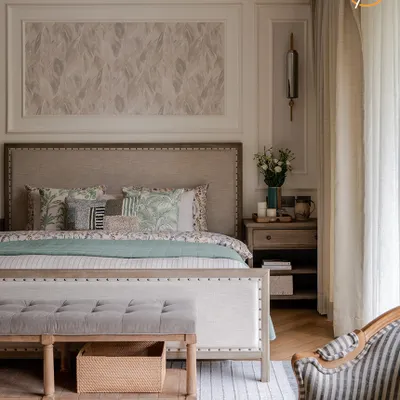 A closer look at the master bedroom's details, showcasing the rich textures of the upholstered bed frame, the rustic wooden bench, and the subtle pattern on the wall panel. Every element is chosen to contribute to a feeling of layered, sophisticated comfort.
