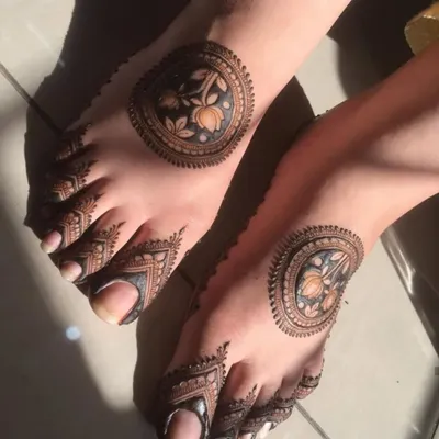 This unique foot design features a bold circular pattern on the top of the foot with detailed work on the toes. The dark fill creates a striking contrast.