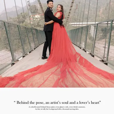 A full-length shot of a couple on a suspension bridge, with the bride's magnificent red trail gown spread across the walkway. A perfect example of a grand, fairytale portrait.