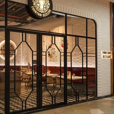 The entrance to Fountain Sizzlers at Palladium, featuring Art Deco-inspired metalwork on the doors and the iconic logo, setting a nostalgic yet sophisticated tone.