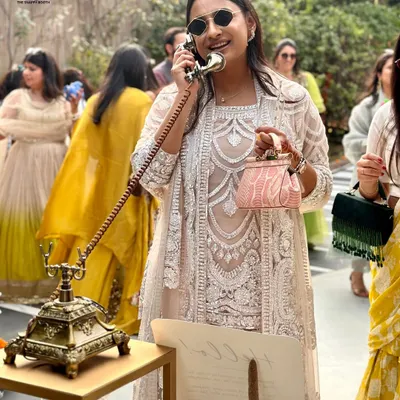 Style and smiles at a daytime wedding event. A guest in beautiful lace attire leaves a message on the Classic Gold phone, which stands out as an elegant and engaging activity for your friends and family.