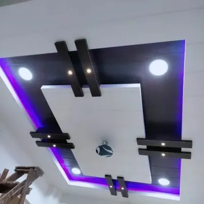 A modern PVC ceiling design with a dark wood finish. The purple cove lighting adds a cool, contemporary vibe, while the spotlights provide excellent functional light.