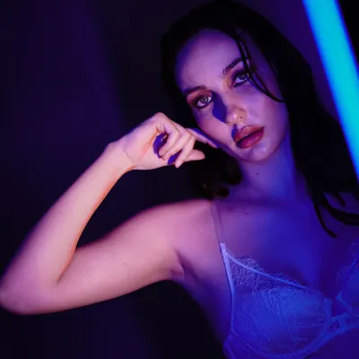 An artistic portrait using a sliver of blue light to create a moody and mysterious atmosphere. The focus is on the model's expression and the play of shadows.