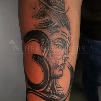 A powerful depiction of Lord Shiva combined with the sacred Om symbol. This black and grey realism tattoo captures a serene yet strong presence.