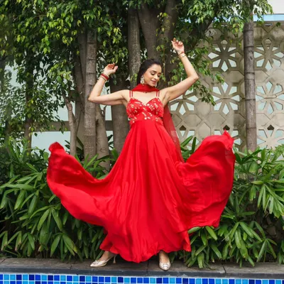 A vibrant and energetic shot from a styled photoshoot. The flowing red anarkali is paired with elegant makeup that is perfect for a Sangeet or reception.