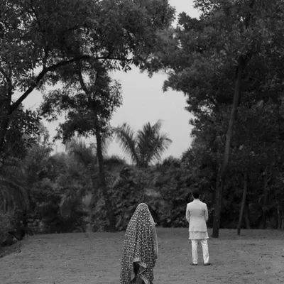 An artistic black and white shot of the bride and groom during their ceremony. The composition creates a sense of journey and togetherness as they walk through a natural landscape.