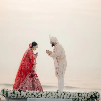 A beautiful moment from a beachside ceremony. The couple greets each other with a traditional namaste against the backdrop of the setting sun and the ocean.