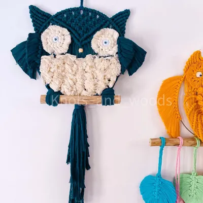 Meet the macrame owl family! This little guy is made with a beautiful teal cord and has a fluffy cream-colored body. He's perched on a natural wooden dowel and is ready to bring some wisdom and charm to your home.