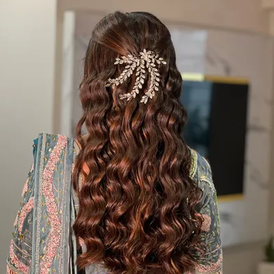 A beautiful example of a half-up, half-down hairstyle with soft, defined waves, perfect for an Engagement or Sangeet. The look is finished with a sparkling hair accessory.