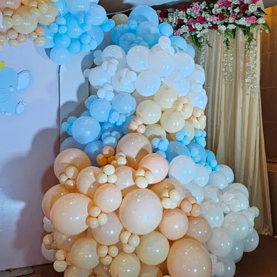 A massive, multi-colored balloon cascade in pastel shades of blue, peach, and white. This type of organic balloon sculpture can transform any corner into a stunning photo opportunity.
