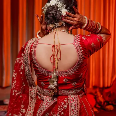 The back of a bride's outfit is often as stunning as the front. This shot highlights the intricate embroidery on her red lehenga and her beautiful floral hairstyle, details that deserve to be remembered.