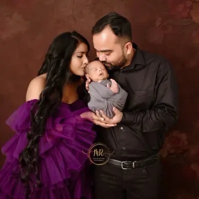 A tender moment as new parents admire their newborn baby. The dark, moody background helps to focus all the attention on the family's loving bond.