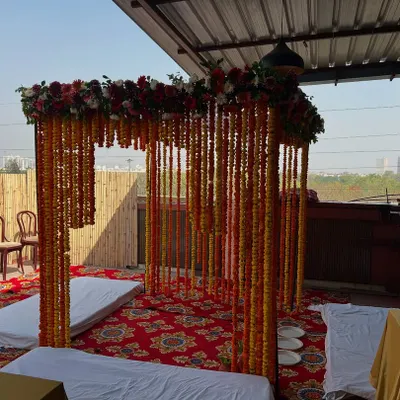 A classic wedding mandap for an outdoor ceremony. This setup uses a canopy of marigold strings and a mixed floral border, perfect for a traditional daytime wedding.