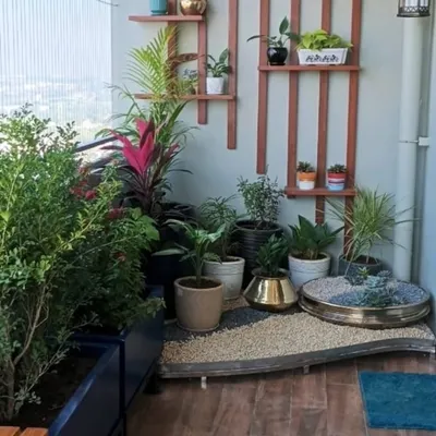 This custom water element for a balcony combines a miniature Zen garden with a gentle water source. Set on a bed of pebbles and surrounded by lush potted plants, it creates a private green escape on a modern apartment balcony.