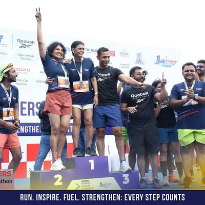 Celebrating a podium finish at the Dream Runners Half Marathon in Chennai. I'm on stage with our victorious runners, sharing in their success.
