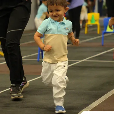 Pure joy in motion. A child runs with a huge smile during a race on Sports Day, embodying the fun and energy of the event.