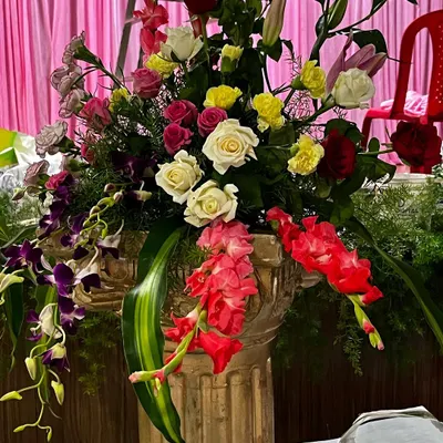 A close-up of a large, vibrant floral arrangement in a classic urn. This piece features a mix of roses, lilies, and orchids, showcasing the quality and variety of flowers I use to create stunning decor.