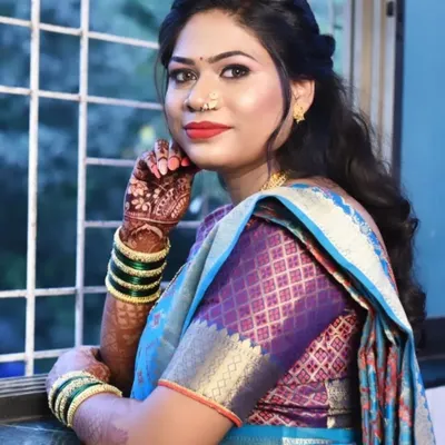 A beautiful Marathi bride ready for her special day. This look features a classic red lip, winged eyeliner, and a traditional nose ring, paired with a half-up hairstyle that is both modern and timeless.