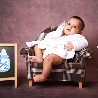 This half-birthday setup is all about personality. Here, the little one looks thoughtfully to the side, showing a calm and curious moment during this fun six-month milestone session.