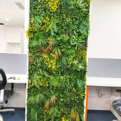 A close-up of a dense and textured artificial green wall we installed in an office. The mix of ferns, grasses, and yellow-accented foliage creates a realistic and vibrant look without any maintenance.