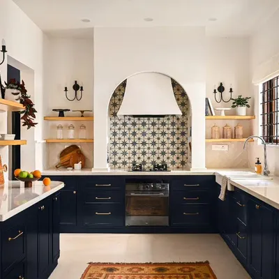 This is the baking kitchen from my Modern Spanish Home project, designed to be the heart of the home. I created distinct zones for every task, from the farmhouse sink under the window to the tall arched display cabinet. The deep blue cabinetry grounds the space, while the custom arched range hood serves as a stunning focal point.
