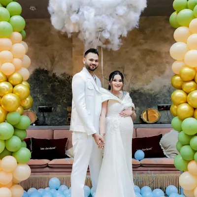 The happy couple after their exciting gender reveal. The floor covered in blue balloons captures the pure joy of the moment.