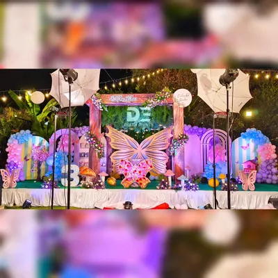 A breathtaking enchanted garden setup for Hithartha's first birthday. This outdoor night event features a massive stage with a giant butterfly centerpiece, mushroom props, and beautiful lighting that creates a truly magical atmosphere.