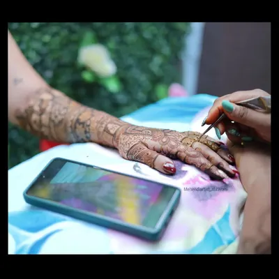 Here I am in my element, focused on creating intricate patterns. I often use a reference on my phone to ensure every detail of a custom design is captured perfectly.
