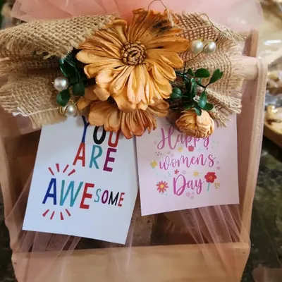 This is a close-up of a hamper I designed for Women's Day. It features a wooden crate base, soft pink tulle wrapping, and a rustic burlap and flower detail, complete with encouraging "You Are Awesome" and "Happy Women's Day" cards.