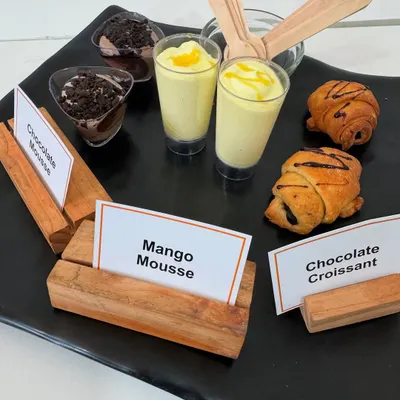 A platter showcasing some of our popular desserts. This selection includes rich Chocolate Mousse, seasonal Mango Mousse, and flaky Chocolate Croissants, perfect for a corporate meet.