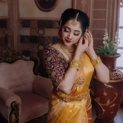 A blouse can truly elevate a saree. Here you can see the intricate embroidery work on this custom purple blouse, perfectly complementing the golden yellow silk saree. We can create a unique design just for you.