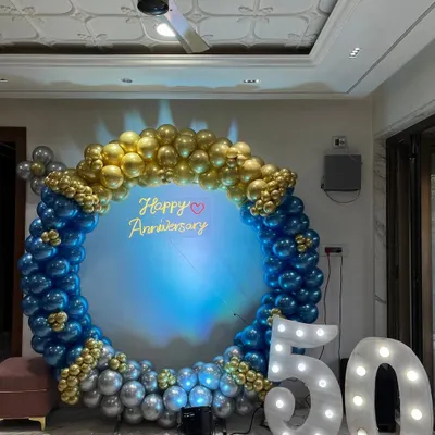This is a grand backdrop I created for a 50th anniversary party. The large balloon ring in blue, gold, and silver, combined with light-up marquee numbers, makes for a perfect photo spot to celebrate a major milestone.