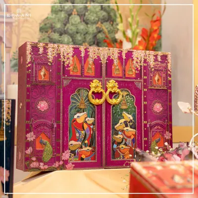 This magnificent invitation hamper is the centerpiece of my Pichwai collection. The doors, adorned with traditional art, open to reveal the wedding invitation, creating a dramatic and unforgettable unboxing experience for your guests.