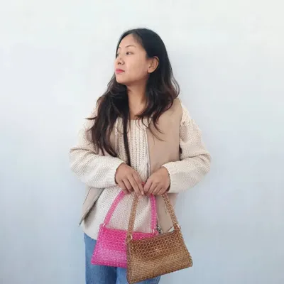 Here I am holding two of my handmade beaded shoulder bags. This shows the size of the bags and how they can be styled. One is a vibrant hot pink and the other is a more subtle metallic bronze, showcasing some of the different colors available.