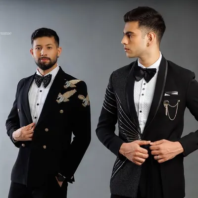 Two of our signature tuxedo designs. One is a double-breasted jacket with gold eagle embroidery on the shoulder, and the other is an asymmetrical design with metallic threadwork.
