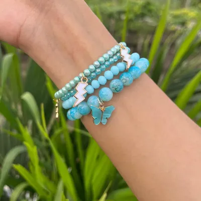 Add a pop of color with this blue beaded bracelet stack. Featuring a mix of textures, lightning bolt charms, and a butterfly, this stack is perfect for adding a fun vibe to any outfit.