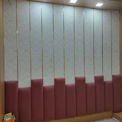 A full view of the custom upholstered headboard wall. The combination of a soft pink padded base and wallpapered upper panels with gold trim creates a sophisticated and complete look.