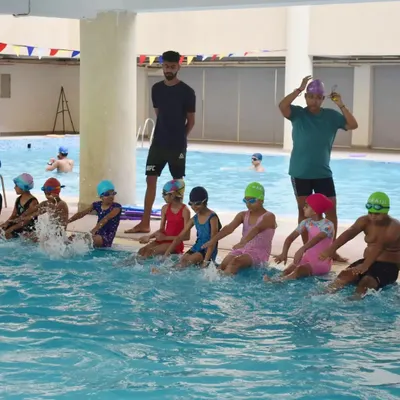 We start with the basics. Here, a group of young learners practices their kicking technique at the edge of the pool under the watchful eye of my coaches.