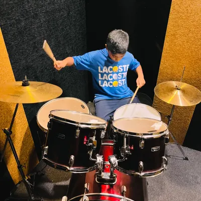 A young drummer in action, fully engaged in his lesson. Our drum classes in HSR Layout are designed to be fun, energetic, and skill-building.