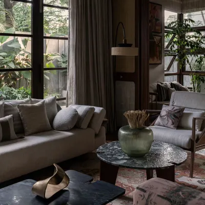 A cozy corner in our Pràna project, where textures and natural light come together. We mixed different fabrics, a unique green marble coffee table, and warm wood tones to create a comfortable and sophisticated living room design.