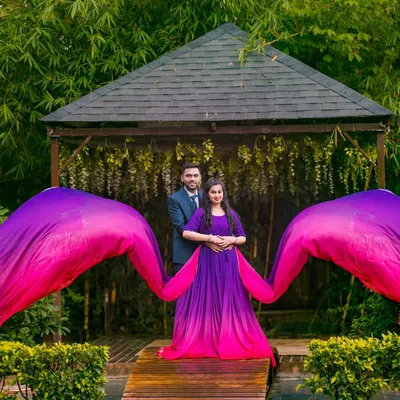 A perfectly symmetrical shot where the vibrant purple and pink gown creates a stunning wing-like effect. This is a great example of a bold, fashion-forward couple portrait taken at the gazebo in Elements Celebrate.