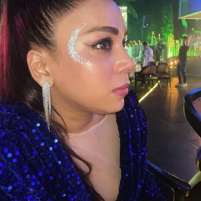 A classic festival look featuring a silver glitter crescent. This design beautifully complements the client's makeup and sequined jacket, perfect for a night of music and dancing.