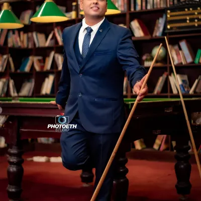 A stylish professional portrait of a client in a library setting with a pool table. This type of environmental portrait adds personality and context, making it more compelling than a standard headshot.