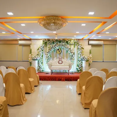 A wide view of a banquet hall set up for a baby shower, showing the floral stage decor, elegant seating arrangement for guests, and ambient lighting.