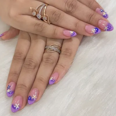 A beautiful example of a soft color transition. These nails feature a purple ombré fade, complemented by small, hand-painted flowers.