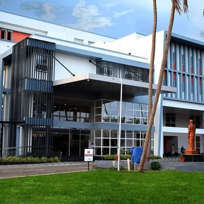 The main facade of the Imbichibava Memorial Co-operative Hospital & Research Center in Tirur, Kerala. The design features a modern exterior with large glass panels and shaded walkways, creating an approachable and professional look.